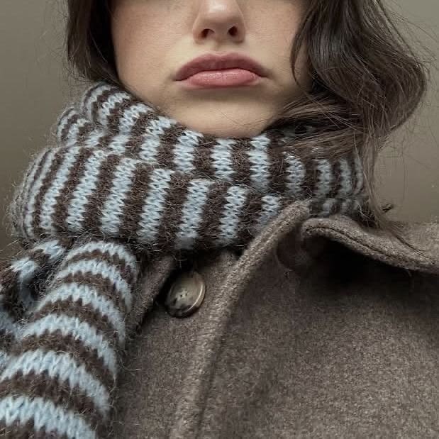 Chunky knitted scarf with brown and light blue stripes worn with a wool coat