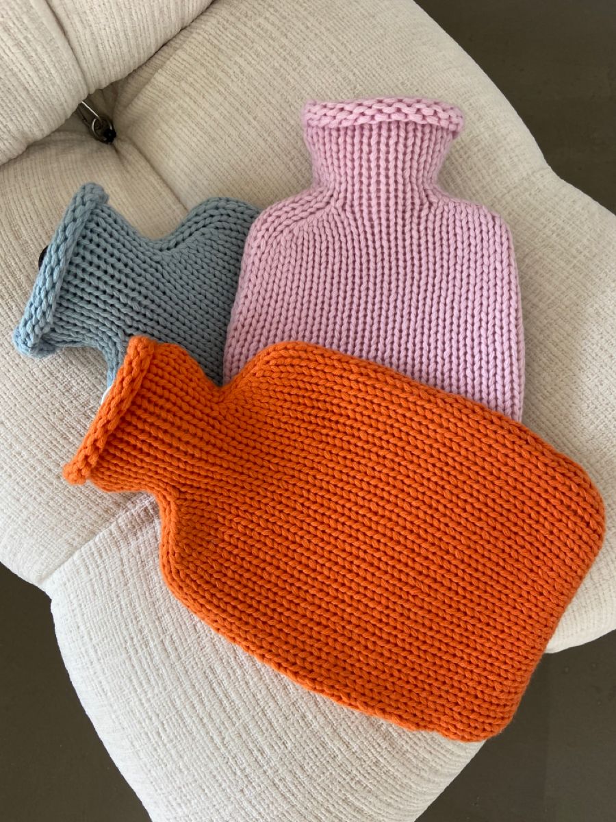 Chunky knitted hot water bottle covers in orange, lilac and blue