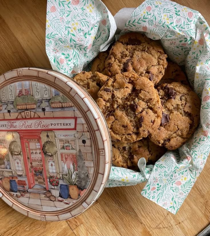 Homemade chocolate chip cookies in a vintage illustrated tin lined with a floral napkin