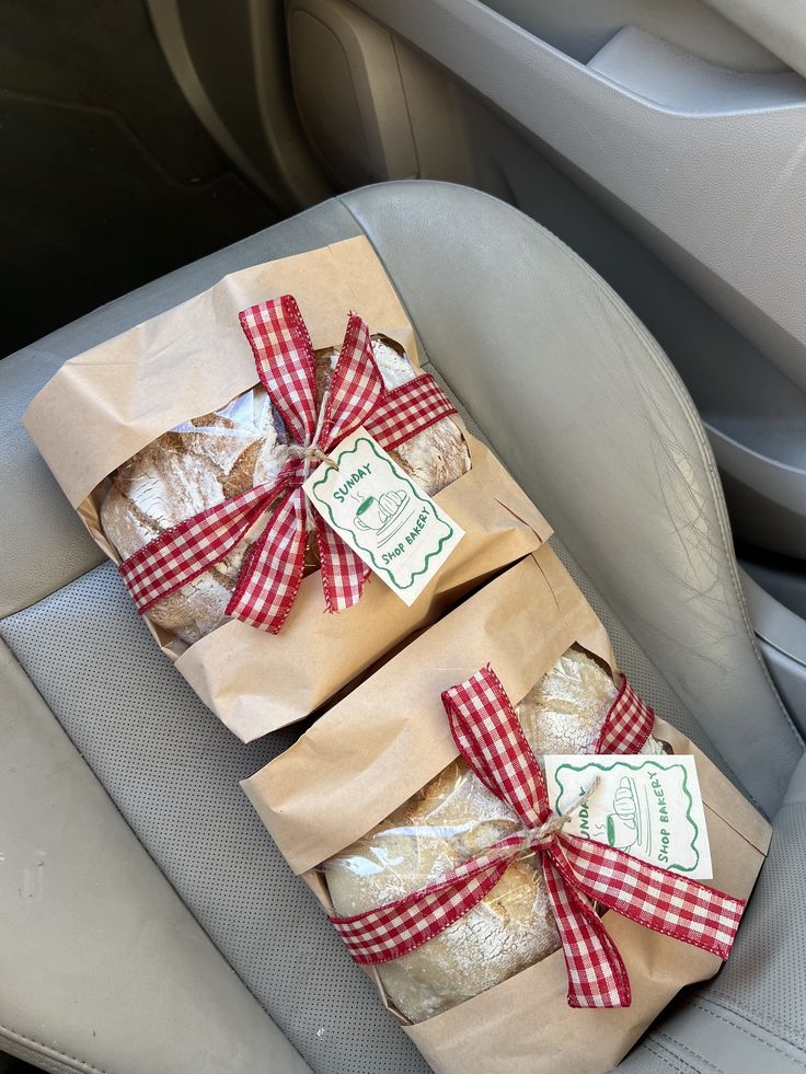 Two sourdough loaves wrapped in kraft paper with red gingham ribbon and bakery tags
