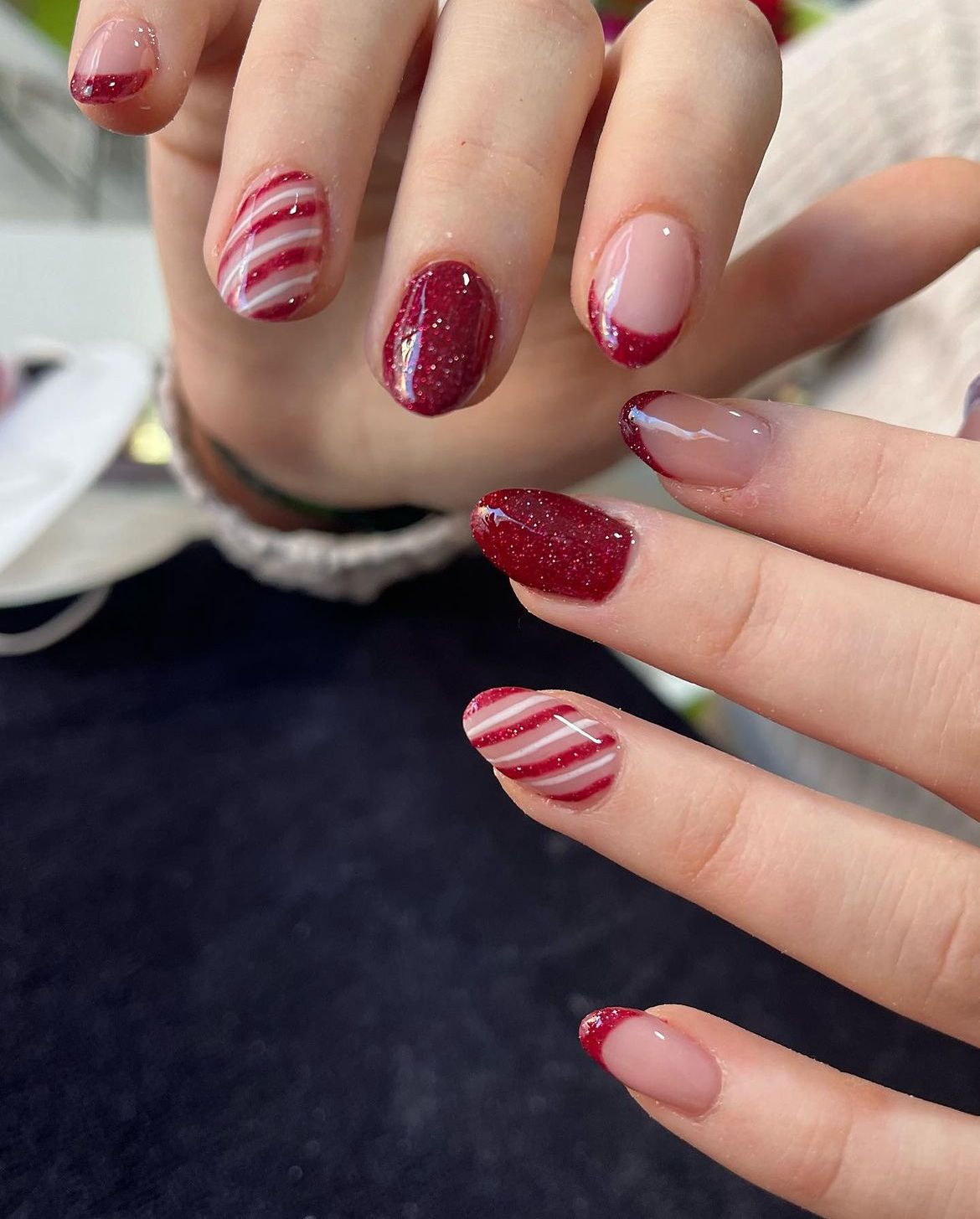 Short mismatched Christmas nails with burgundy glitter, glitter French tips and candy stripes