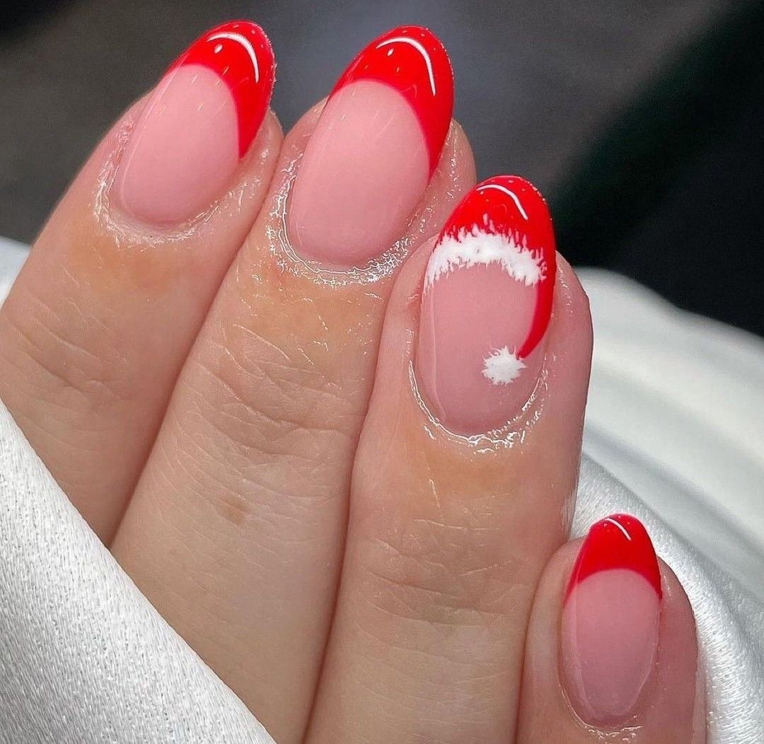 Red French tip Christmas nails with a fluffy Santa hat accent