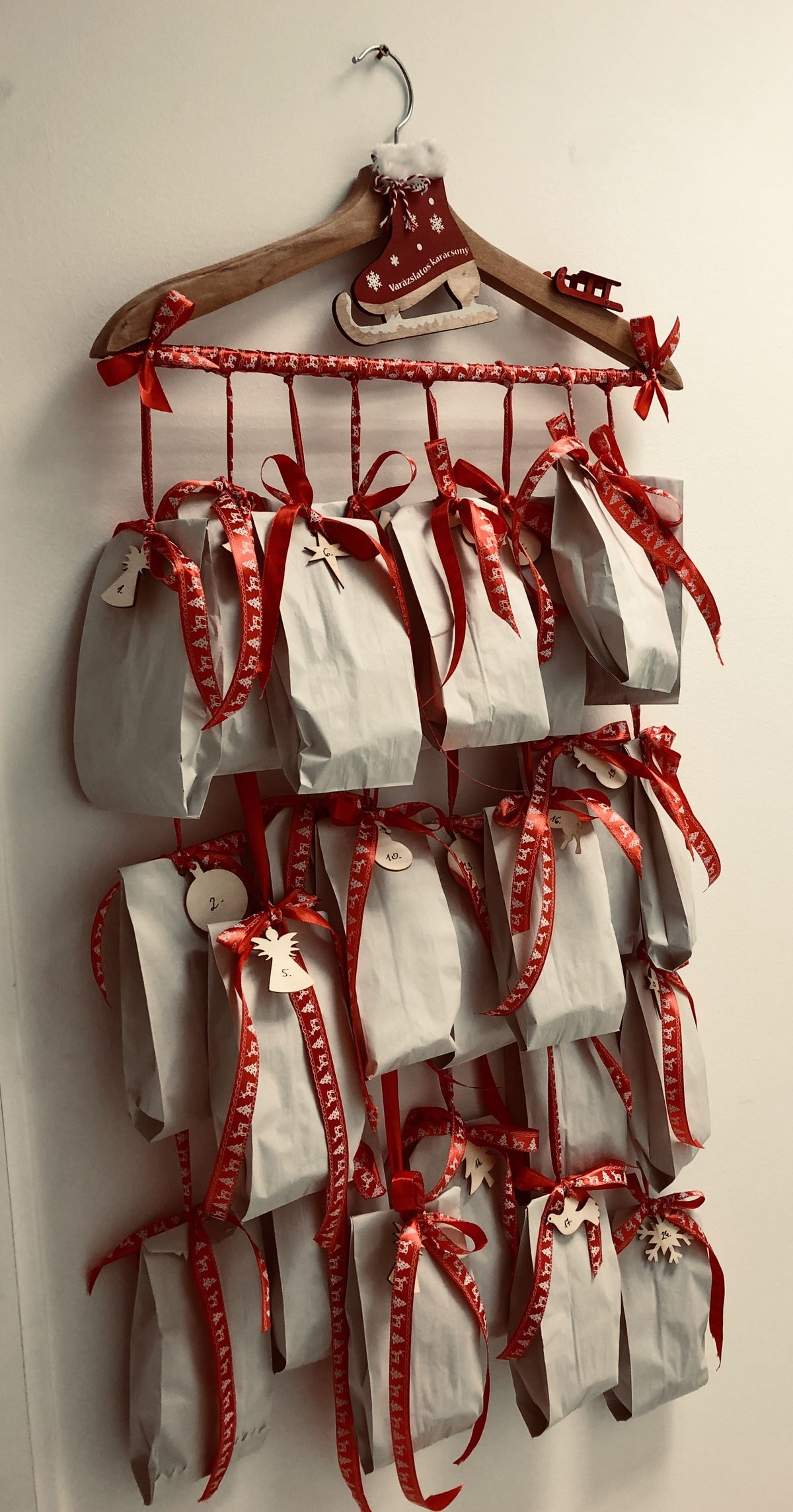 Wooden coat hanger DIY advent calendar with white paper bags tied on with red ribbon