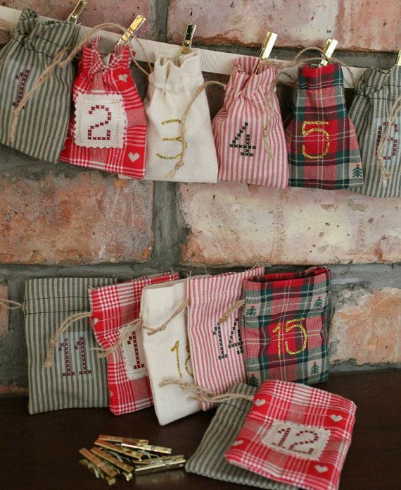 Plaid and striped fabric drawstring pouches with cross stitch numbers pegged along a ribbon