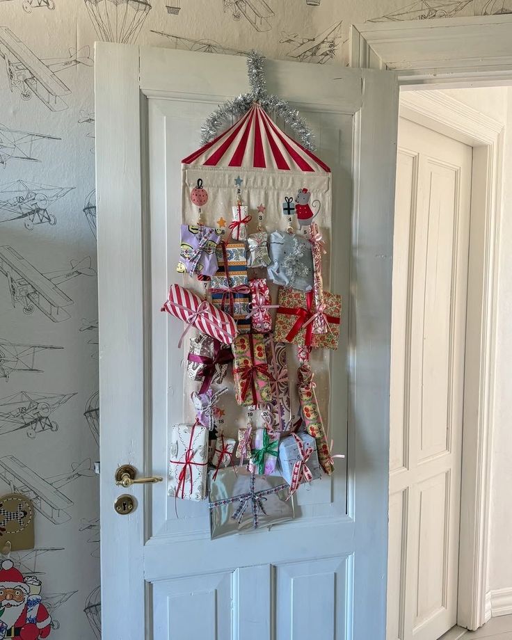 Red and white striped circus tent pocket advent calendar with wrapped gifts hanging on a door
