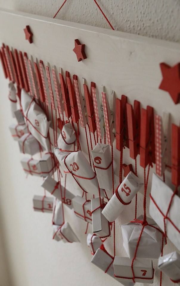 Red painted wooden pegs on a white board holding small white advent parcels tied with red string