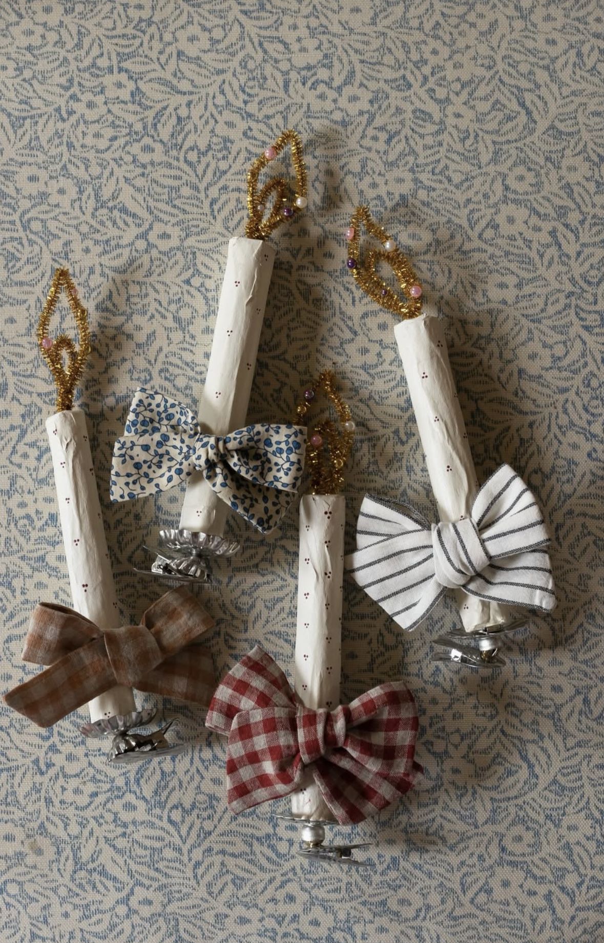 White clay candle ornaments with gold pipe cleaner flames, fabric bows and silver clip bases