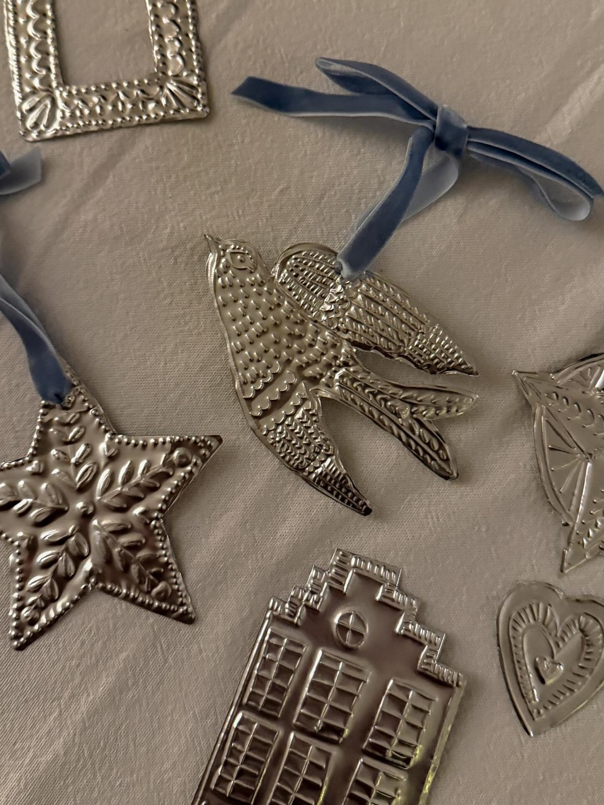 Embossed silver tin ornaments shaped like a bird, star and house with blue velvet ribbon
