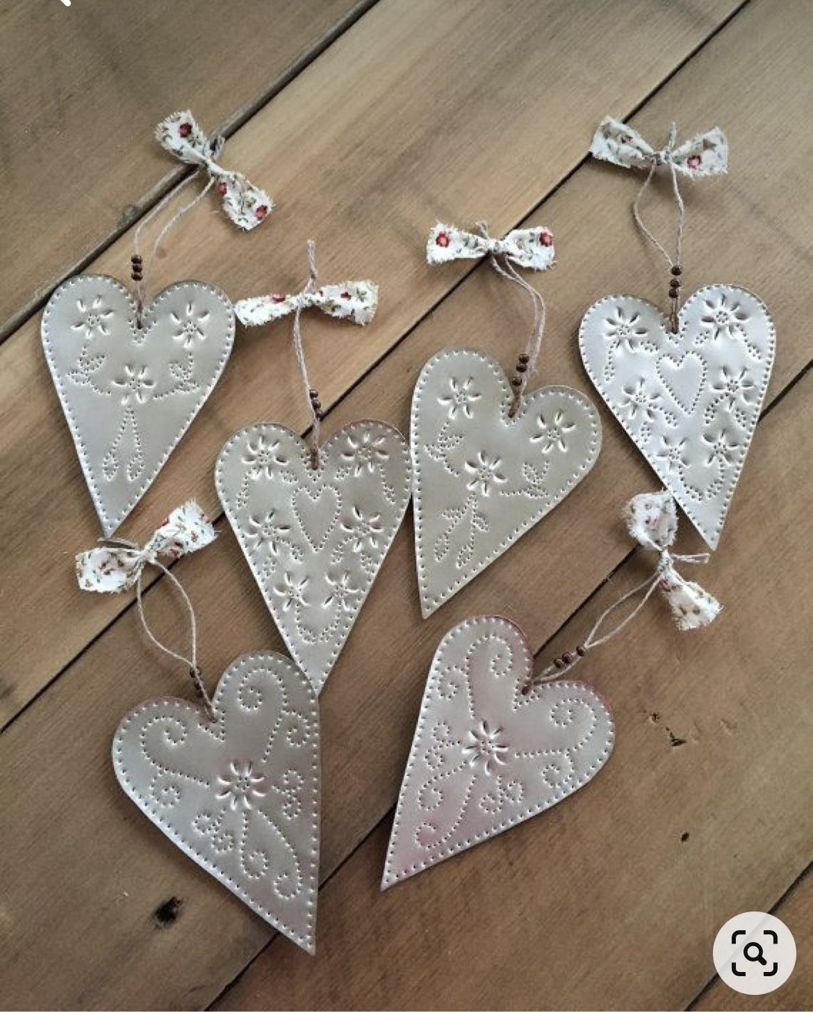 Punched tin heart ornaments with floral dot patterns, beaded twine hangers and fabric bows