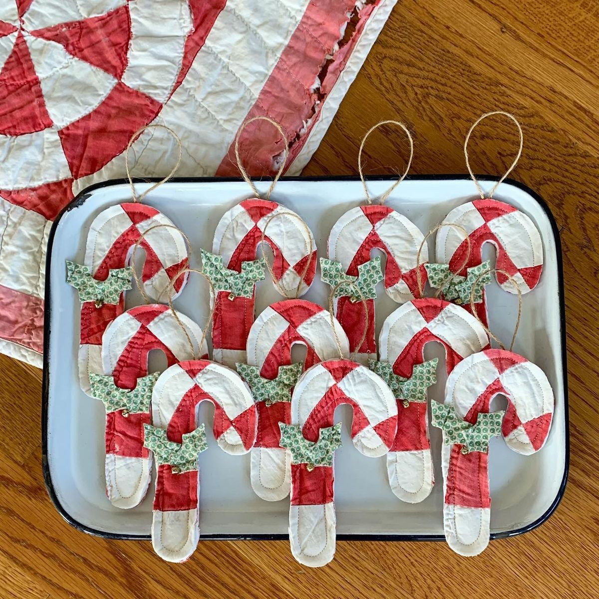 Candy cane ornaments cut from a red and white vintage quilt with green fabric holly and twine hangers