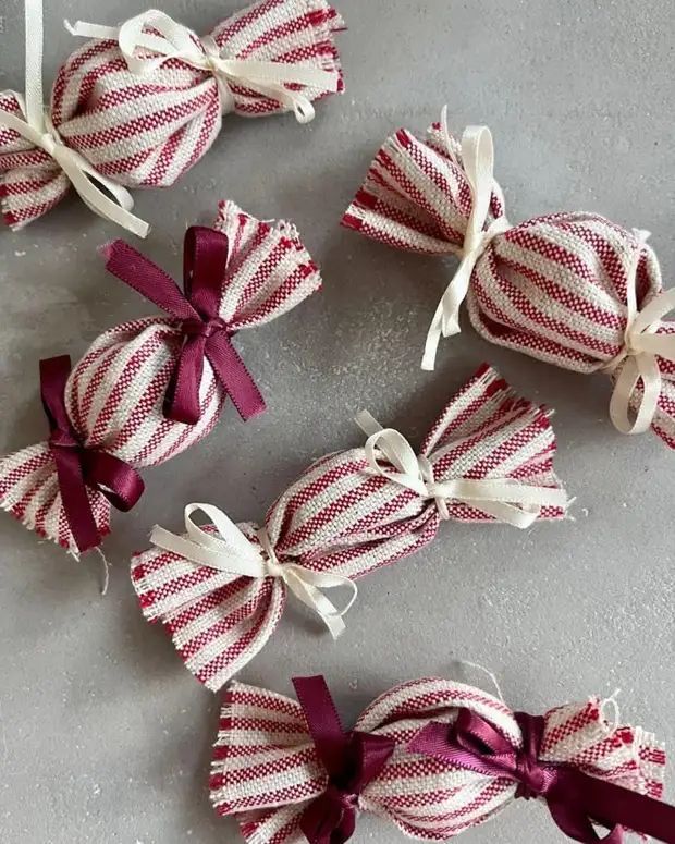 Red and white striped fabric ornaments wrapped like lollies and tied with cream and burgundy ribbon