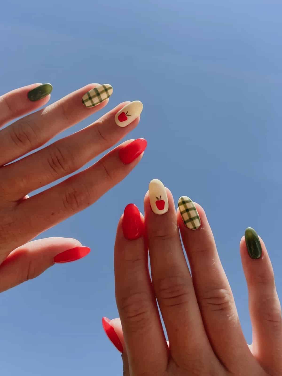 Almond nails in red and olive green with a cream gingham accent and a red apple design