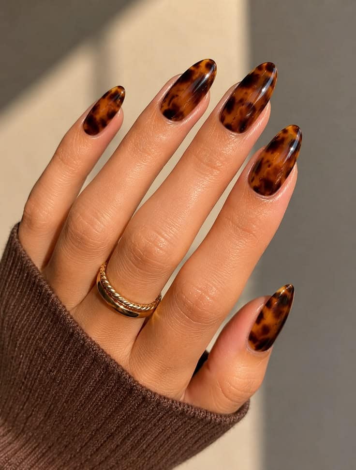 Long almond nails in glossy tortoiseshell with a gold ring