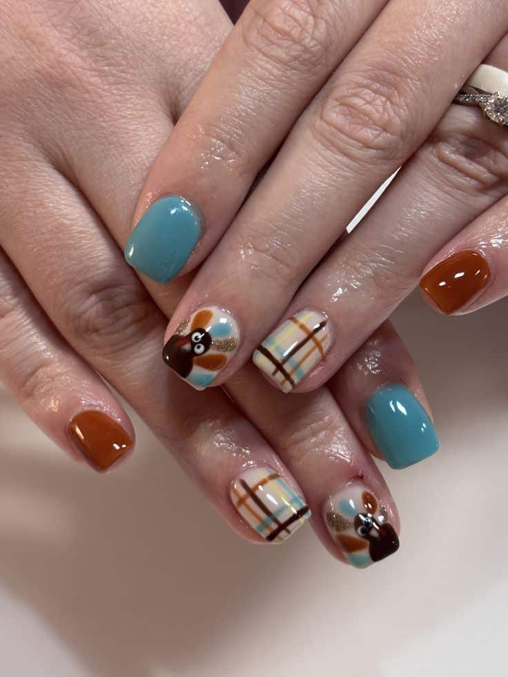 Short square nails in teal and rust with plaid accents and turkey designs with glitter feathers
