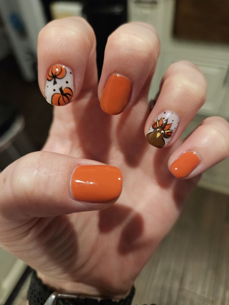 Short burnt orange nails with white accent nails featuring painted pumpkins and a turkey
