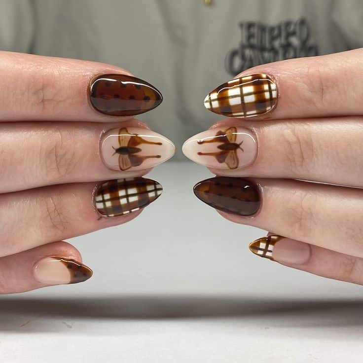 Almond nails with brown jelly plaid, polka dots and a painted moth on a milky nude base