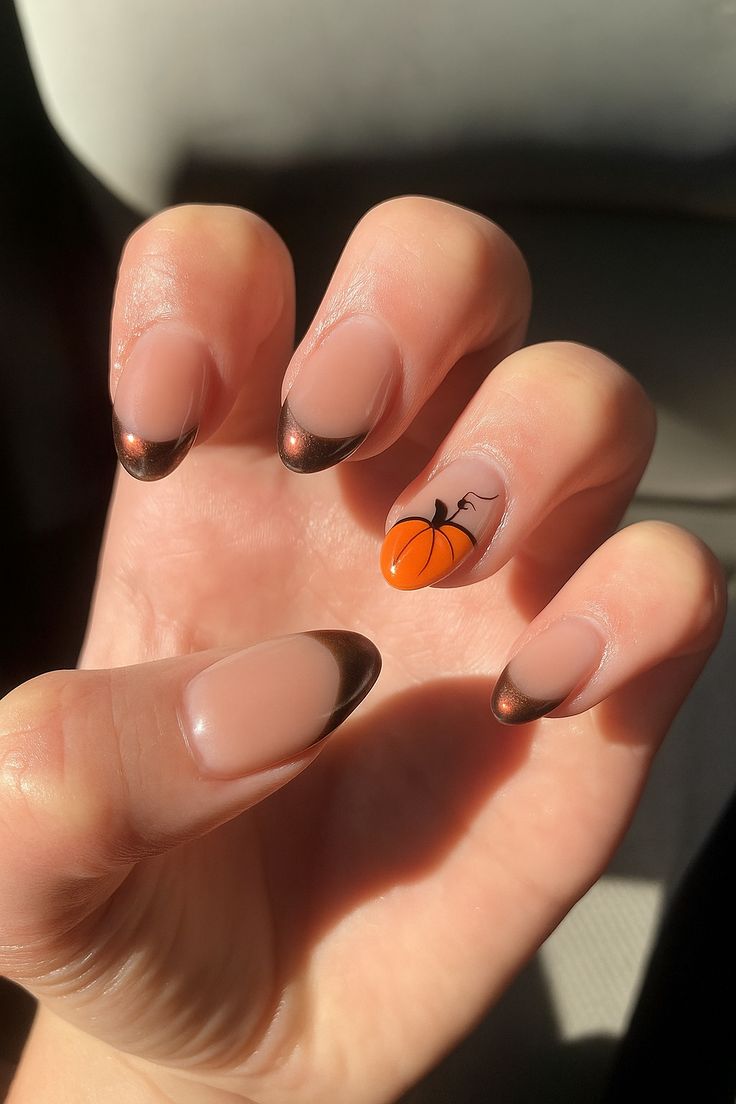 Almond nails with bronze chrome French tips and an orange pumpkin accent nail