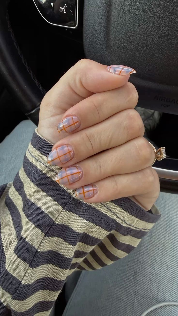 Sheer lilac and grey jelly nails with burnt orange plaid lines